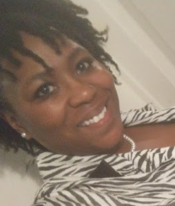 Michelle is a black woman with short, twisted black hair. She is smiling at the camera while wearing a zebra print blouse.